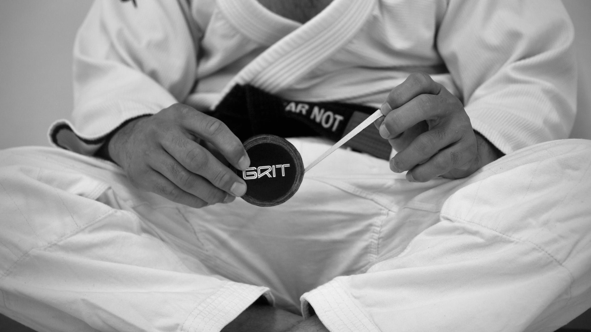 Person in a martial arts uniform holding a Grit Tape against a neutral background